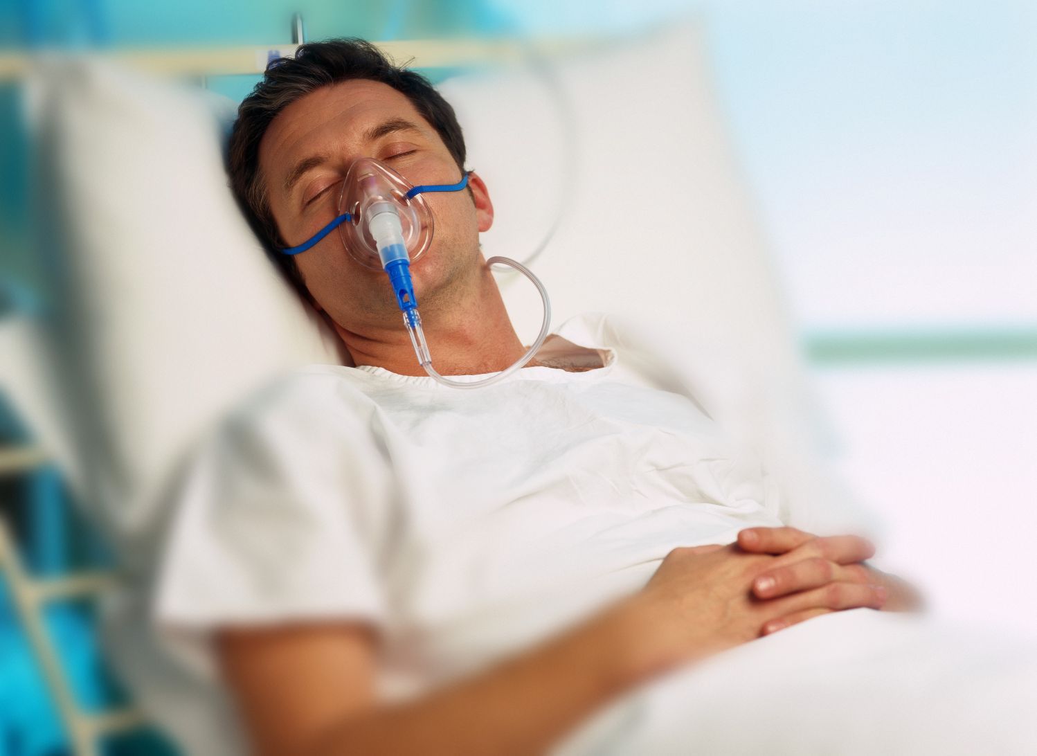 Portrait of a man with an oxygen mask in a hospital bed